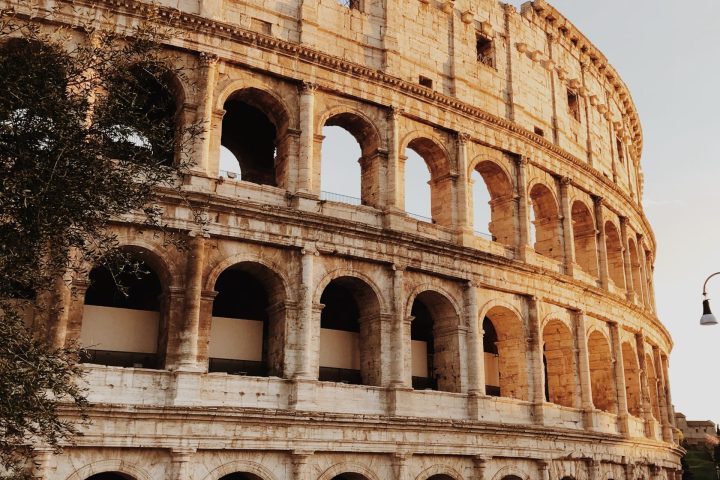 a large stone building with many windows with Colosseum in the background